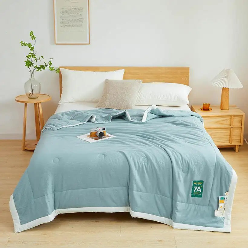 Bed with light blue comforter and pillows in a bedroom setting