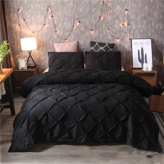 Black textured comforter set on a bed with string lights and decor in the background