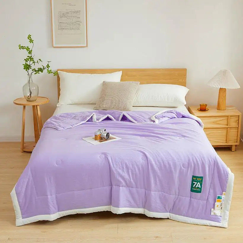 Bed with purple comforter and wooden headboard in a bedroom setting