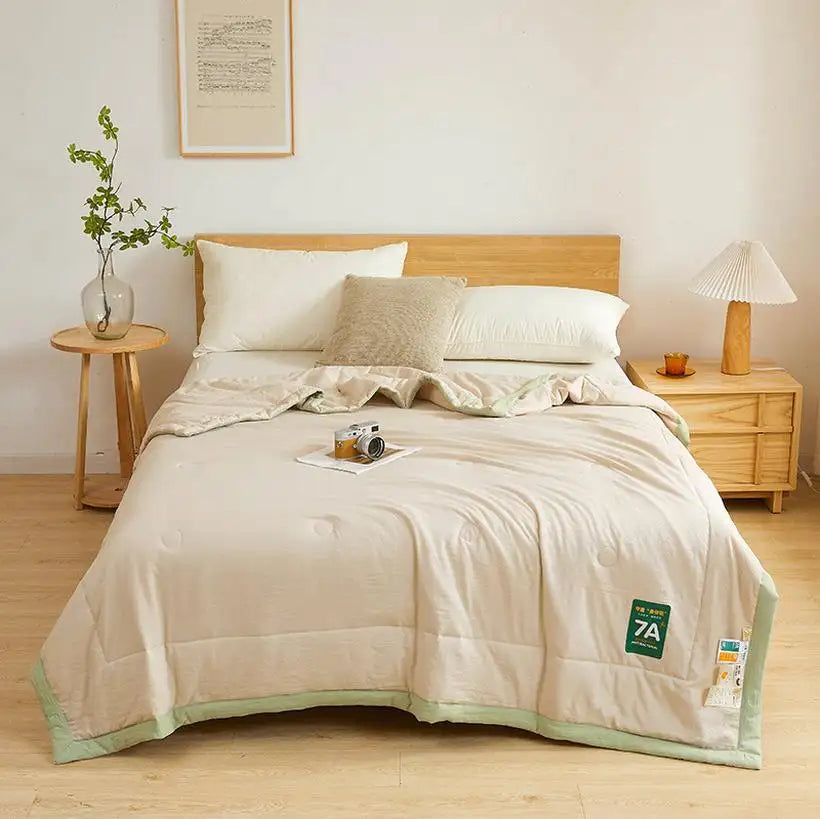 Neatly made bed with beige comforter and pillows in a bedroom setting.