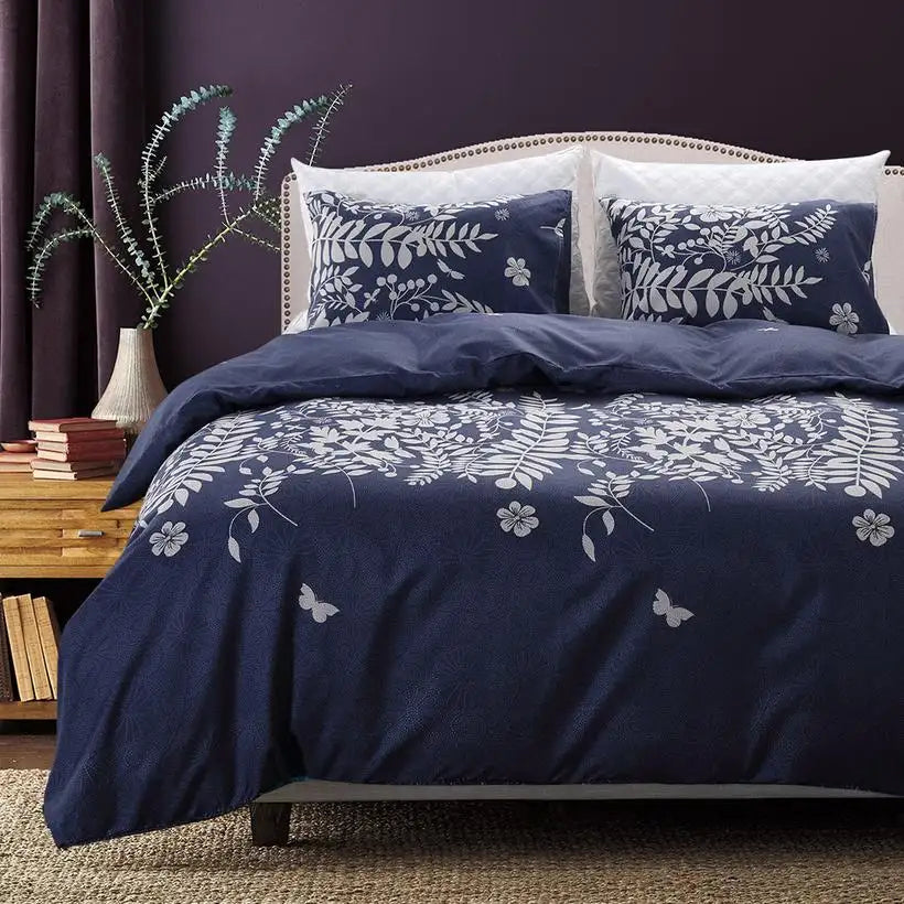 Navy blue floral bedding set on a bed with a wooden nightstand and books in the background.
