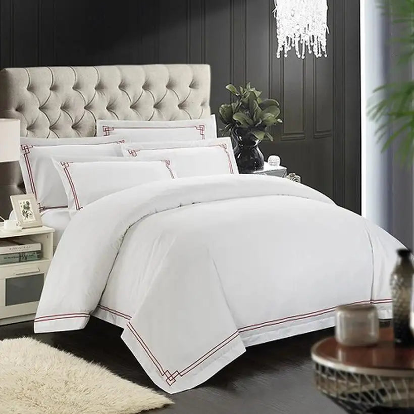 White bedding set with red trim on a bed in a bedroom setting.