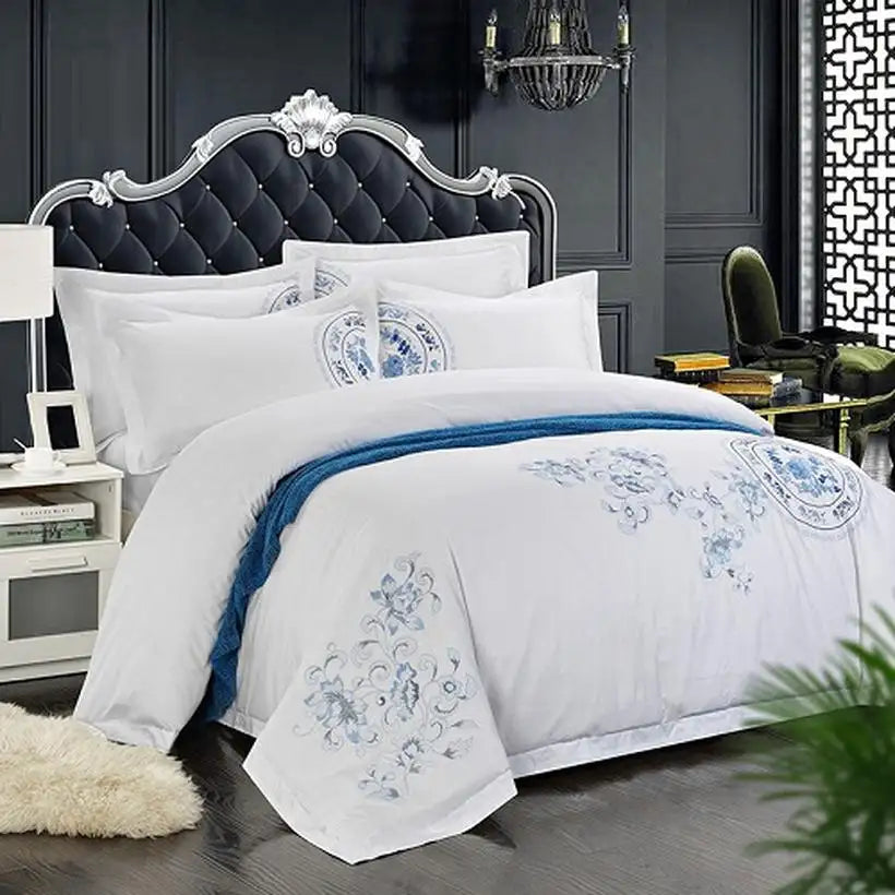 White bedding set with blue floral embroidery on a bed in a stylish bedroom.