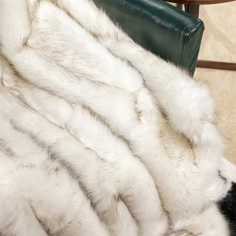 Close-up of a white fur throw on a green chair.