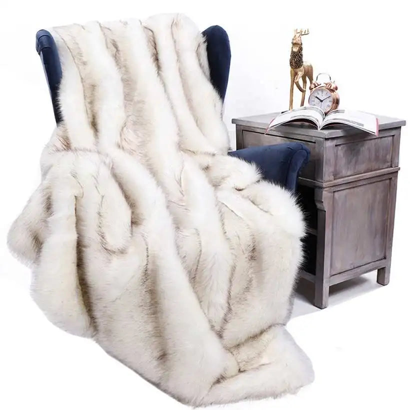 White faux fur throw blanket draped over a chair next to a wooden side table with decorative items.