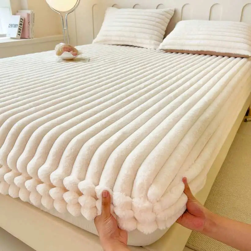 Person holding a textured white blanket over a bed in a bedroom setting