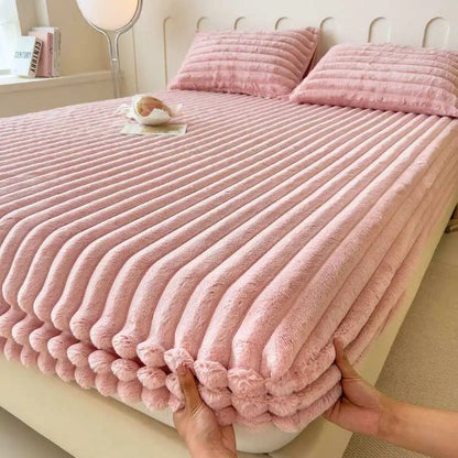 Pink textured blanket being held over a bed in a bedroom setting.