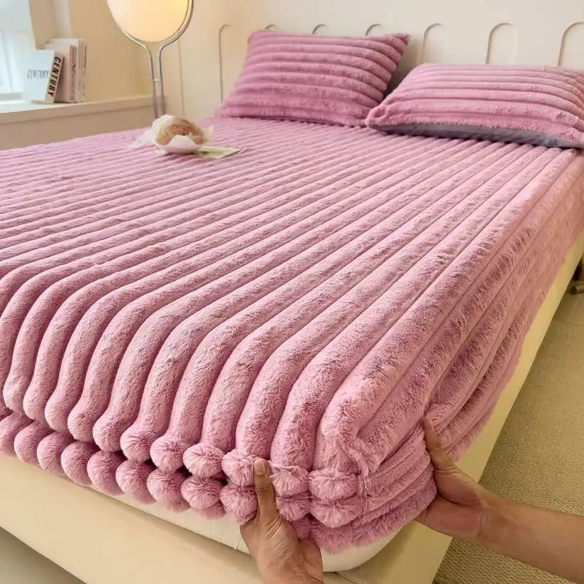 Pink textured bedspread being adjusted on a bed in a bedroom setting.