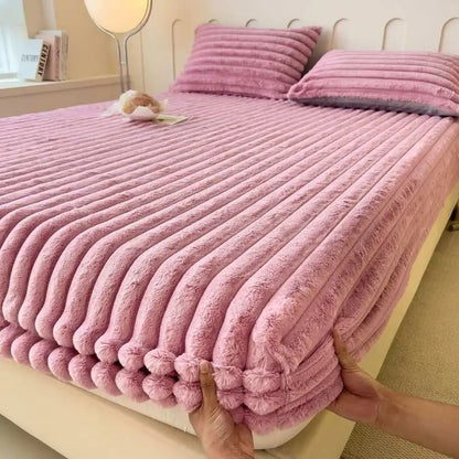 Pink textured bedspread being adjusted on a bed in a bedroom setting.