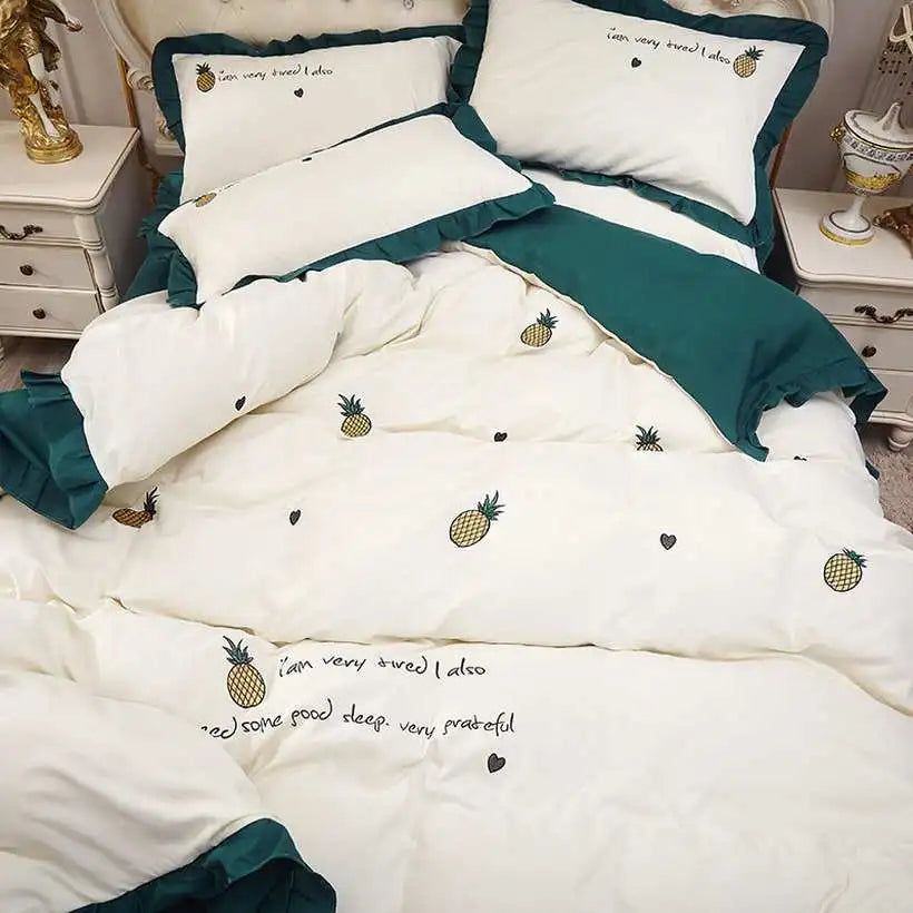 White bedding set with pineapple patterns and text on a bed, with green accents.