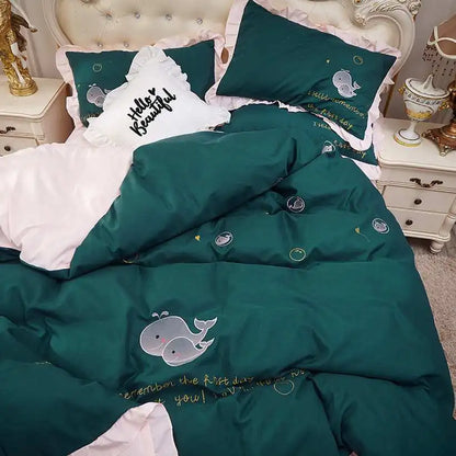 Green bedding set with whale embroidery on a bed in a bedroom setting.