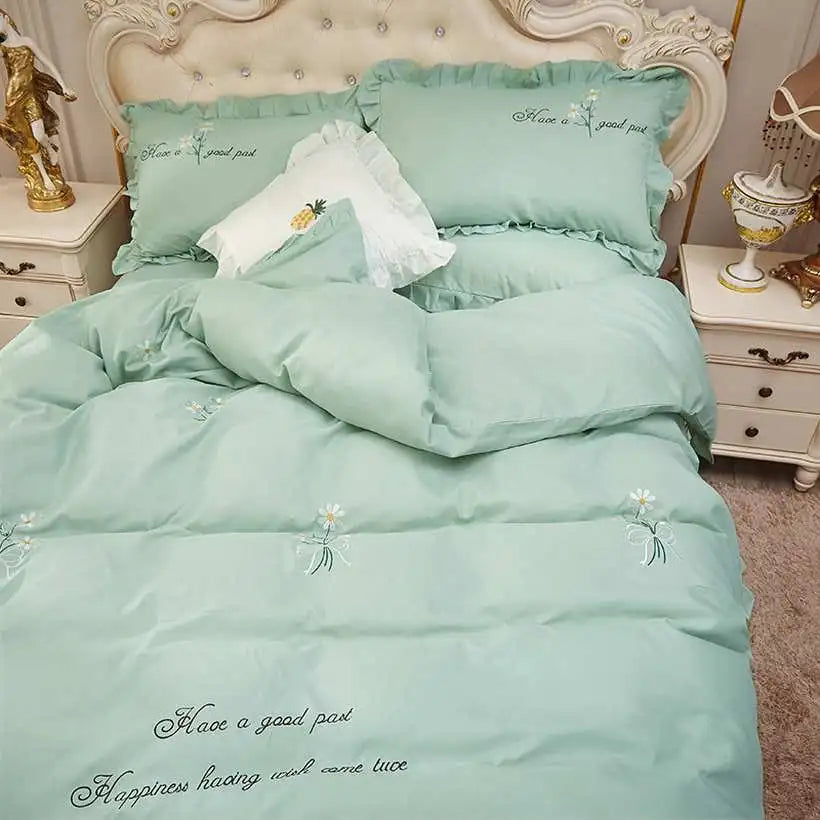 Mint green bedding set with floral embroidery on a bed in a bedroom setting.