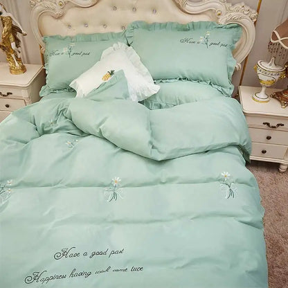 Mint green bedding set with floral embroidery on a bed in a bedroom setting.