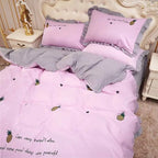 Pink and gray bedding set with pineapple designs on a bed.