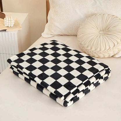 Black and white checkered blanket on a bed with pillows and a nightstand.