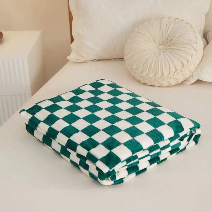 Green and white checkered blanket on a sofa with decorative pillows.