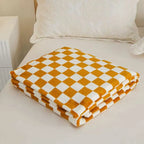 Checkered orange and white blanket on a bed with pillows