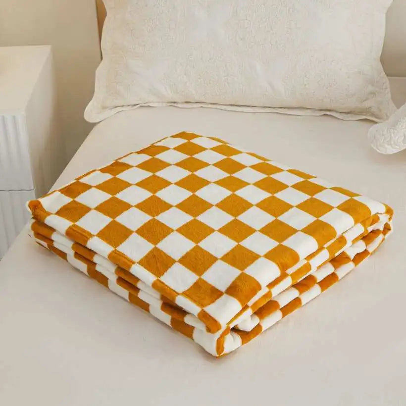 Checkered orange and white blanket on a bed with pillows