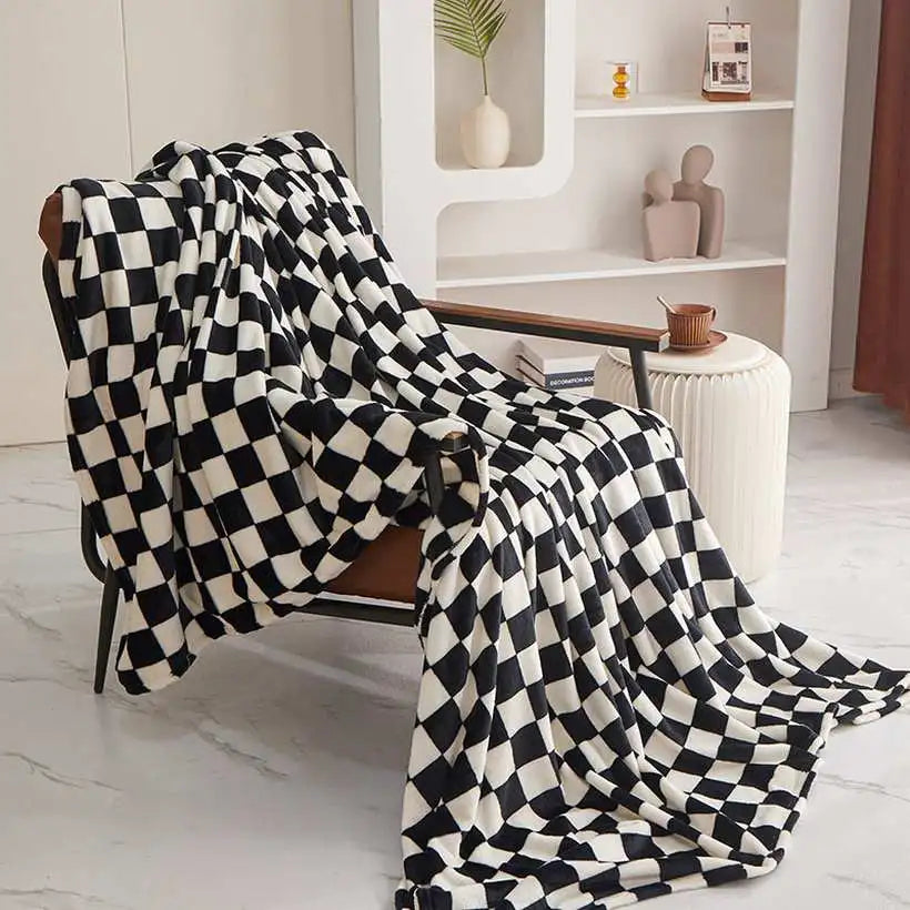 Black and white checkered blanket draped over a chair in a room with a white bookshelf.