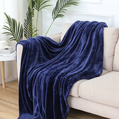Navy blue blanket draped over a beige sofa in a living room setting with plants and a coffee table.
