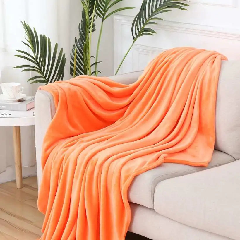 Orange blanket draped over a white sofa with a plant in the background