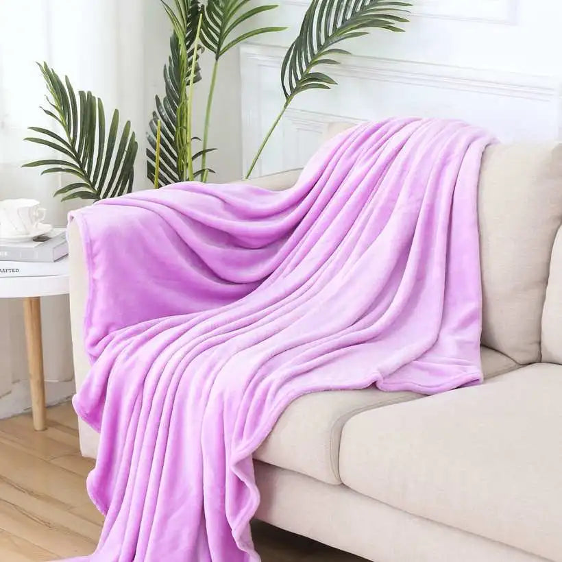 Purple blanket draped over a beige sofa with plants in the background