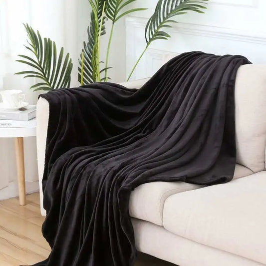 Black blanket draped over a white sofa with plants in the background
