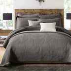 Gray textured comforter set on a bed with wooden headboard and side tables.
