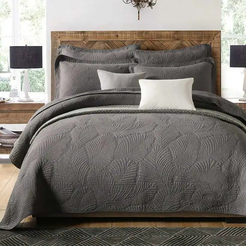 Gray textured comforter set on a bed with wooden headboard and side tables.