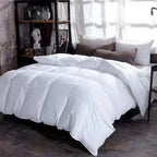 White comforter on a bed with pillows in a room with a bookshelf and window.